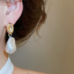 Nahaufnahme eines französischen Barockperlenohrrings mit Goldstecker am Ohr des Models