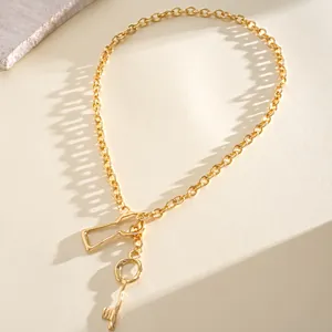 Detailopname van een goudkleurige ketting met unieke hangers in de vorm van een sleutel en slot