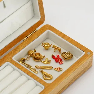Variety of 18K gold plated stainless steel charms displayed in a wooden jewelry box.