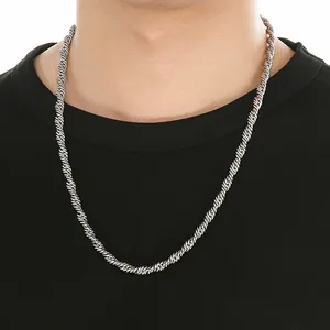 Detail van een zilveren roestvrijstalen touwketting op een zwart t-shirt.