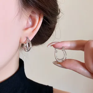 Primo piano di eleganti orecchini a cerchio a doppio strato in argento indossati