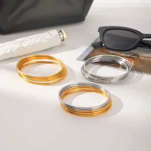 Multiple 18k gold and silver stainless steel bangle sets in a lifestyle setting