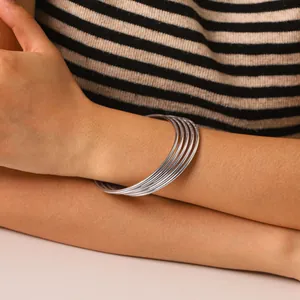 Detailed shot of a five-piece set of minimalist silver stainless steel bangles on arm.