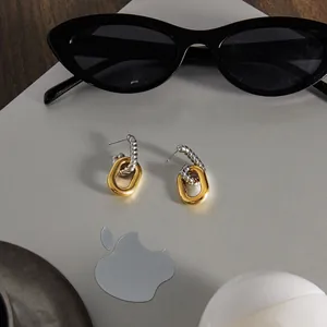 Detailed view of two-tone geometric stud earrings paired with black sunglasses