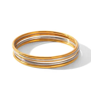 Detailed view of five-piece stacked stainless steel bangles in gold and silver finish