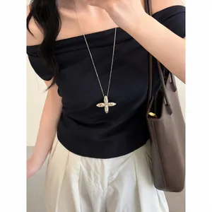 Detailed view of a silver cross star pendant necklace on a black off-shoulder top