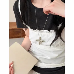 Close-up of a silver cross star pendant necklace with quilted texture on a model