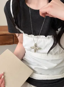 Detailed shot of a silver puffy star pendant necklace on a model wearing a ruffled top
