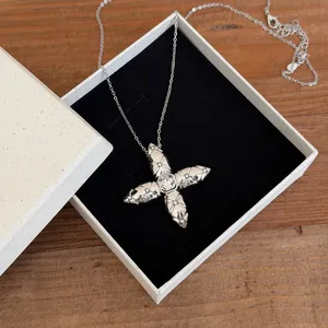 Elegant silver starburst pendant necklace with sparkling stones shown in a gift box setup.