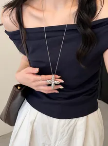Detail view of a stylish silver star-shaped cross pendant necklace on an Asian model.