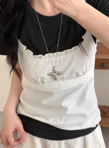 Large silver star cross pendant necklace styled on a model wearing white camisole