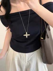 Detailed view of a silver star pendant necklace worn with a black off-the-shoulder top