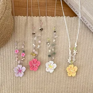 Detailansicht farbenfroher Perlenketten mit Blumenanhängern in vier zarten Pastelltönen