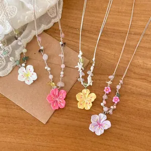 Detailaufnahme von farbenfrohen Perlenketten mit großen floralen Harzanhängern.