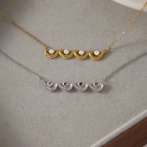 Close-up of gold and silver wave pendants with sparkling zircon inlays on grey tray