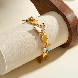 Close-up of a gold-plated stainless steel butterfly bracelet with pastel enamel details.