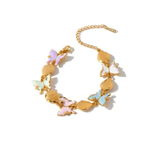 Detailed view of colorful enamel butterfly and gold drop charms on stainless steel bracelet