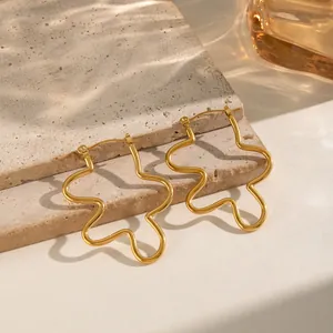 Detailed macro view of 18K gold plated wavy hoop earrings resting on natural stone
