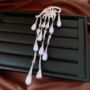 Close-up of elegant silver eye brooch with pearl tassels on jewelry tray