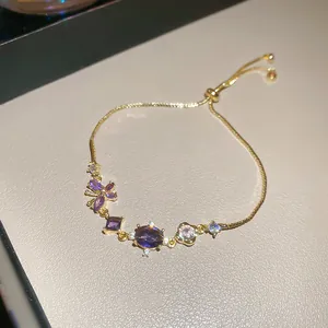 Elegant gold adjustable bracelet featuring purple zircon stones and floral charms