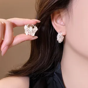 Close-up of sweet flower basket earrings with white blossoms and rhinestones detail