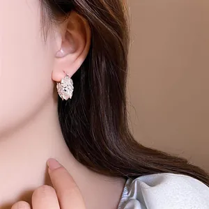 Elegant floral earrings with pearls and rhinestones worn by a model close-up