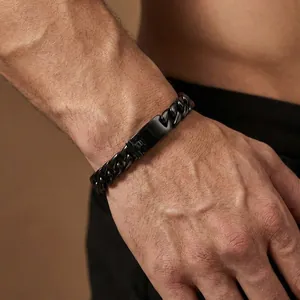 Close-up of a men's polished black stainless steel Cuban link bracelet on a wrist