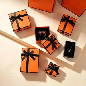 Elegant orange gift boxes with black ribbons and assorted jewelry for a luxury presentation
