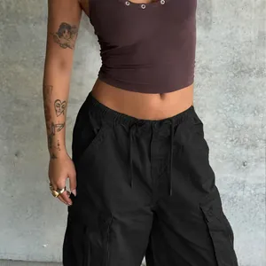 Detail of cargo pants showing drawstring waist and large flap pockets on black fabric