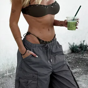 Detail of dark olive bikini with eyelets and loose grey cargo trousers with side pockets