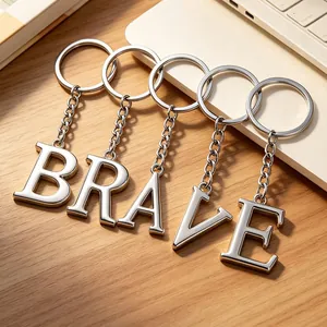 Lot de porte-clés en métal poli épelant BRAVE sur un bureau en bois naturel