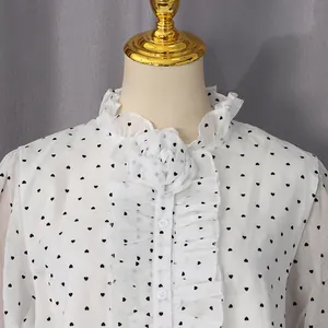 Detail of ruffle collar with 3D floral accent and heart print on white chiffon shirt