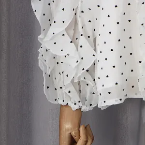 Close-up of white blouse featuring heart polka dot print and ruffled elastic cuffs