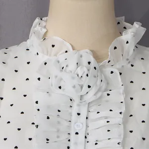 Close-up of white chiffon blouse collar with black heart print and ruffle flower detail