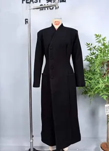 Detail of slim-fit black wool coat with side buttons, stand collar and large pockets