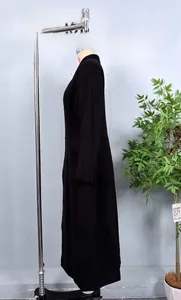 Detail of a black mid-length wool coat with a stand collar and side button waist design