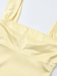 Détail du tissu satiné mat et de l'encolure carrée plissée sur la robe moulante jaune clair