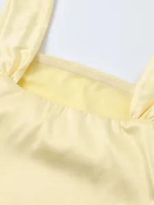 Détail du décolleté carré de la robe en satin jaune avec plis et bande antidérapante