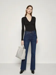 Détail du haut noir ajusté à col en V et du jean évasé à taille haute sur modèle