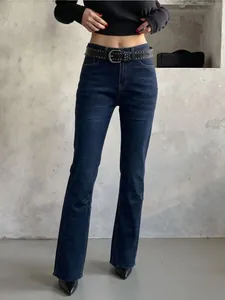 Détail du jean bleu foncé à taille haute avec ourlet effiloché et ceinture cloutée