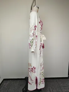 Détail d'une robe longue fleurie vintage avec ceinture à la taille et franges bordeaux
