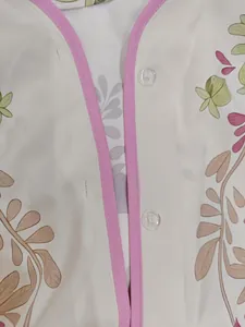 Gros plan du décolleté en V avec liseré rose et imprimé floral sur tissu léger
