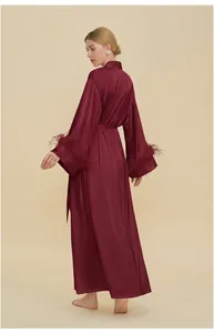 Detailed view of burgundy satin robe featuring elegant feather trim on the sleeves