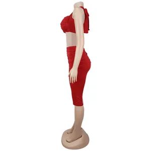 Detail of red two-piece set featuring a halter crop top and pleated high waist skirt