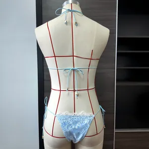 Détail de la dentelle et des ferrets dorés sur le bas du bikini bleu clair au dos