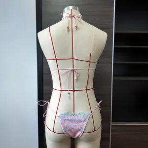 Détail du bas de bikini en dentelle rose avec bordure bleue et perles dorées
