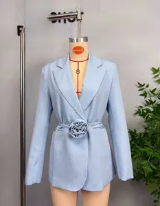 Gros plan sur un blazer bleu clair pour femme avec une grande fleur en tissu à la taille