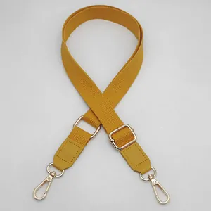 Detail of adjustable yellow canvas bag strap with golden metal swivel lobster clasps