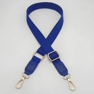 Close-up of dark blue woven bag strap with golden metal clasps and adjustable buckle