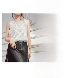 Detail showing white sequin sleeveless top with intricate embroidery and black satin skirt